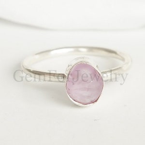 May include: A silver ring with a pink gemstone. The gemstone is a rough cut and has a natural, organic shape.