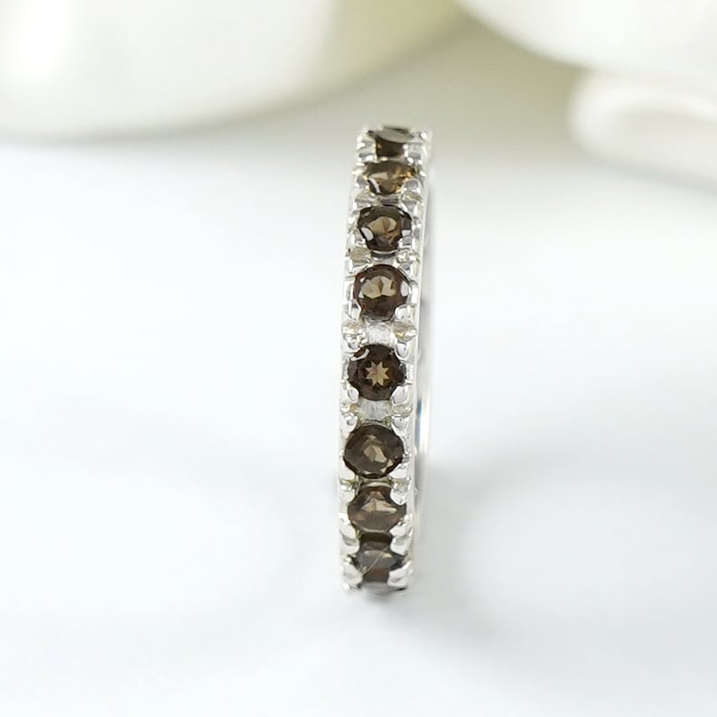 May include: A silver band ring with a row of brown gemstones.