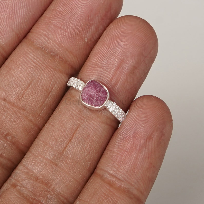 Peut inclure: Une bague en argent avec une pierre pr&eacute;cieuse rose carr&eacute;e. La bague a une bande textur&eacute;e.