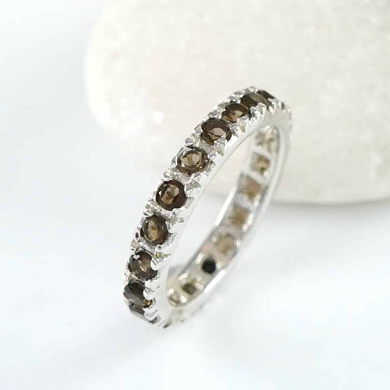 May include: A silver band ring with a row of brown gemstones around the entire band.