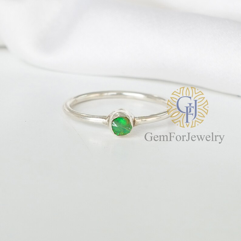 May include: A silver ring with a green opal gemstone. The ring is simple and elegant, perfect for everyday wear.