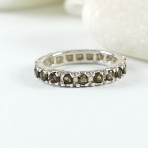 May include: A silver band ring with a row of brown gemstones.