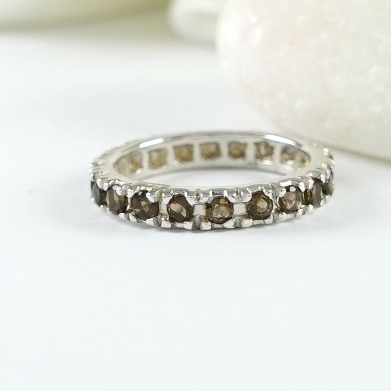 May include: A silver band ring with a row of brown gemstones.