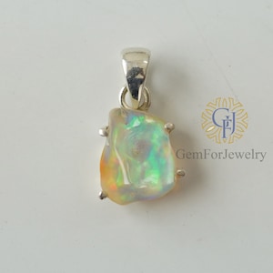 May include: A silver pendant featuring a natural opal gemstone with iridescent colours. The opal is set in a silver bezel and has a rough, irregular shape.