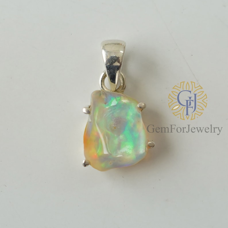 May include: A silver pendant featuring a natural opal gemstone with iridescent colours. The opal is set in a silver bezel and has a rough, irregular shape.