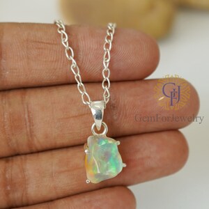 May include: A silver chain necklace with a pendant featuring a large, iridescent opal gemstone. The opal is set in a silver bezel and has a unique, irregular shape.