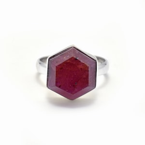 May include: A silver ring with a large, hexagonal, faceted ruby gemstone.