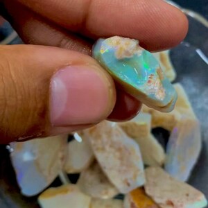 Puede incluir: Una colecci&oacute;n de piedras de &oacute;palo en bruto de varios tama&ntilde;os y formas. Las piedras son una mezcla de colores blanco, marr&oacute;n y azul verdoso. Las piedras est&aacute;n en un cuenco de vidrio transparente.