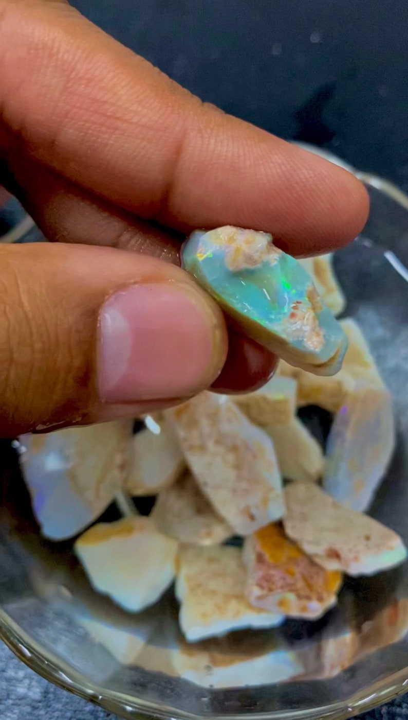 Puede incluir: Una colecci&oacute;n de piedras de &oacute;palo en bruto de varios tama&ntilde;os y formas. Las piedras son una mezcla de colores blanco, marr&oacute;n y azul verdoso. Las piedras est&aacute;n en un cuenco de vidrio transparente.