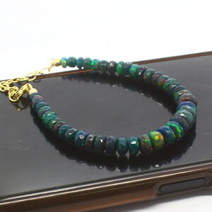May include: A bracelet made of dark green and black opal beads with a gold clasp.