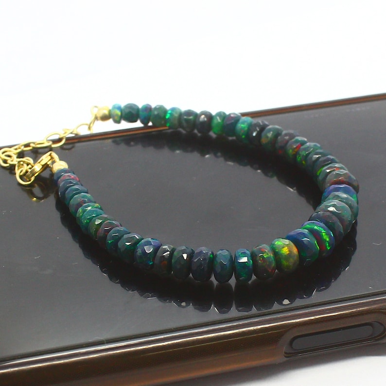 May include: A bracelet made of dark green and black opal beads with a gold clasp.