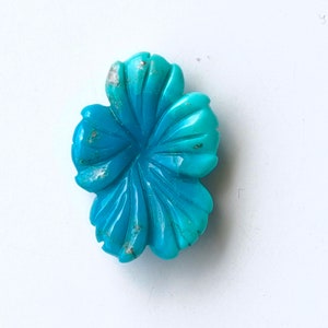 May include: A carved turquoise flower pendant in a vibrant blue color. The flower has a detailed design with multiple petals.