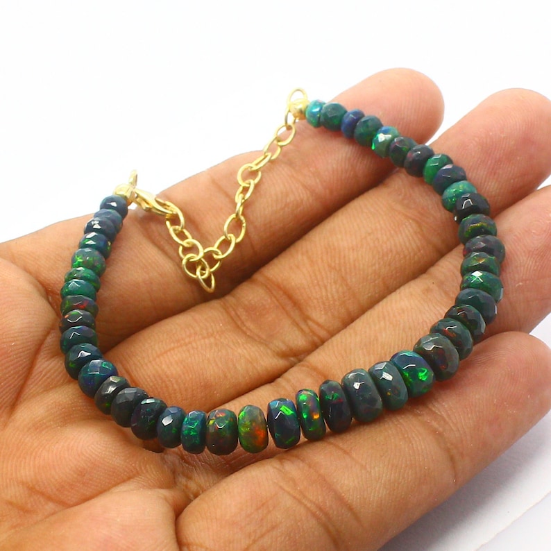 May include: A green and black opal gemstone bracelet with a gold chain clasp.