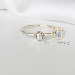 May include: A delicate silver ring with a single white pearl set in a bezel setting. The ring is simple and elegant, perfect for everyday wear.