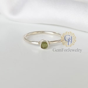 May include: A silver ring with a small, green gemstone set in the center.