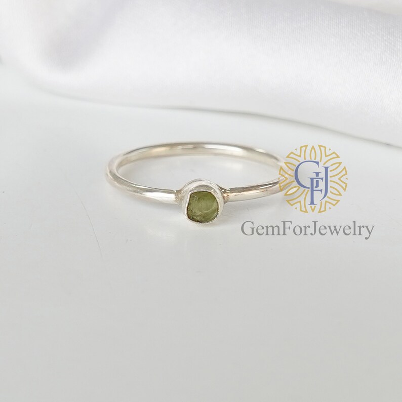 May include: A silver ring with a small, green gemstone set in the center.