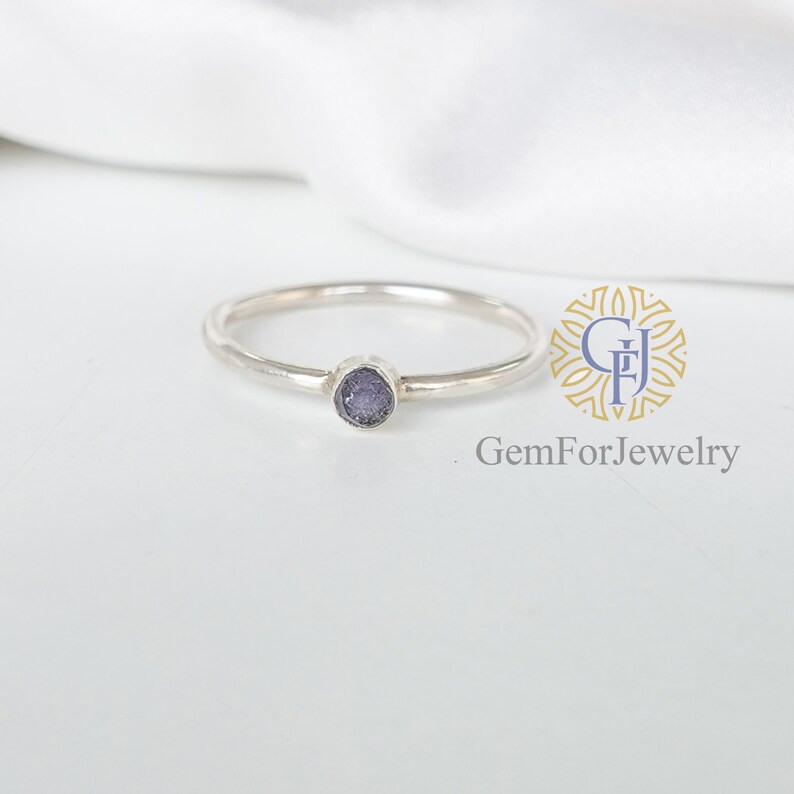 May include: A silver ring with a small, round, purple gemstone.