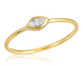 May include: A delicate gold ring with a single marquise-shaped diamond set in a bezel setting.