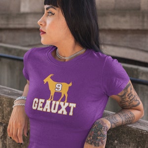 May include: Purple t-shirt with a gold silhouette of a goat with the number 9 on its side and the word "GEAUX" printed below.