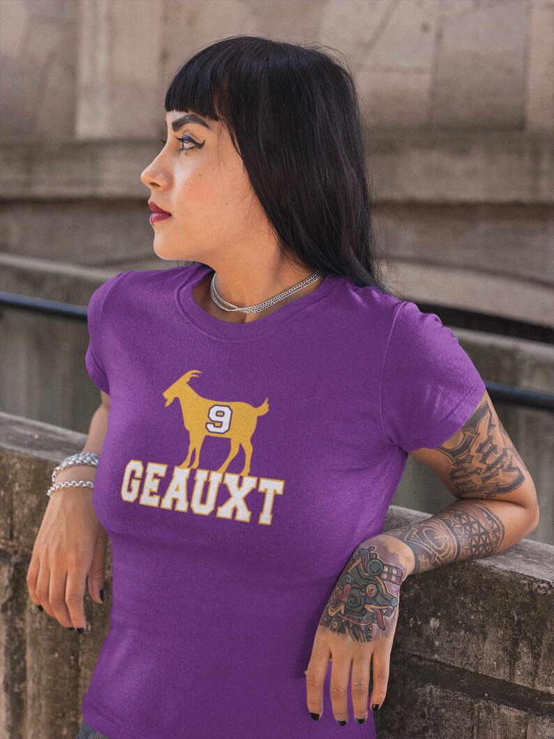 May include: Purple t-shirt with a gold silhouette of a goat with the number 9 on its side and the word "GEAUX" printed below.