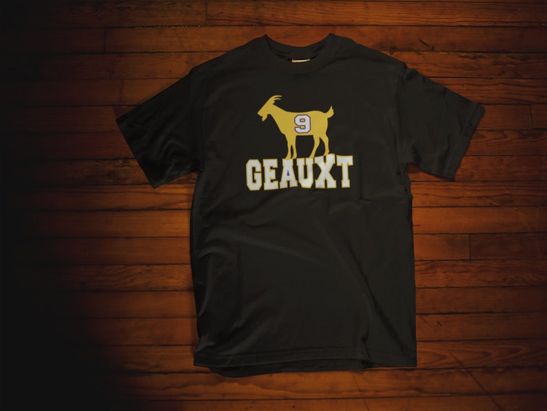 May include: Black t-shirt with a gold silhouette of a goat wearing a jersey with the number 9. The text "GEAUX" is printed below the goat.