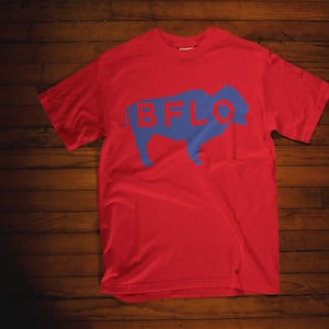 May include: Red t-shirt with a blue buffalo silhouette and the text "BFLO" printed on the front.