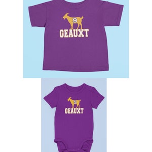 May include: Purple short-sleeved t-shirt and bodysuit with a gold silhouette of a goat with the number 9 on it and the text "GEAUX'T" underneath.