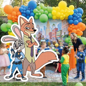 Puede incluir: Escena de fiesta con un arco de globos multicolores. Recortes de cart&oacute;n de los personajes de Zootopia Judy Hopps y Nick Wilde est&aacute;n en primer plano. Se ven ni&ntilde;os y adultos.