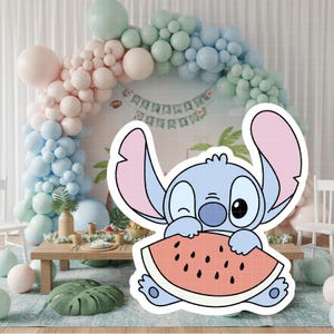 Może przedstawiać: Jasnoniebieska postać z kresk&oacute;wki mrugająca okiem i trzymająca plaster arbuza. Postać ma duże uszy z r&oacute;żowymi wnętrzami. Tło obejmuje łuk z balon&oacute;w w pastelowych kolorach i nakrycie stołu.