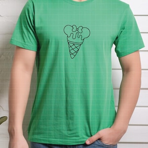 May include: A bright green short-sleeved t-shirt featuring a centered black line art graphic of an ice cream cone topped with a rounded shape resembling mouse ears and a small bow centered between the ears on the top of the ice cream scoop.