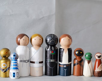 May include: A set of Star Wars character peg dolls, including Luke Skywalker, Princess Leia, Darth Vader, Han Solo, Chewbacca, R2-D2, C-3PO, Yoda, and Jabba the Hutt. The dolls are painted in their iconic colors and features.