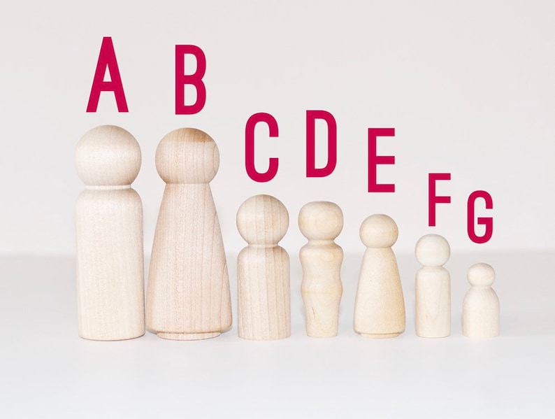 May include: Seven wooden peg dolls of varying sizes, arranged in a line from largest to smallest. The dolls are unpainted and have a natural wood finish. The letters A through G are printed above the dolls in red.