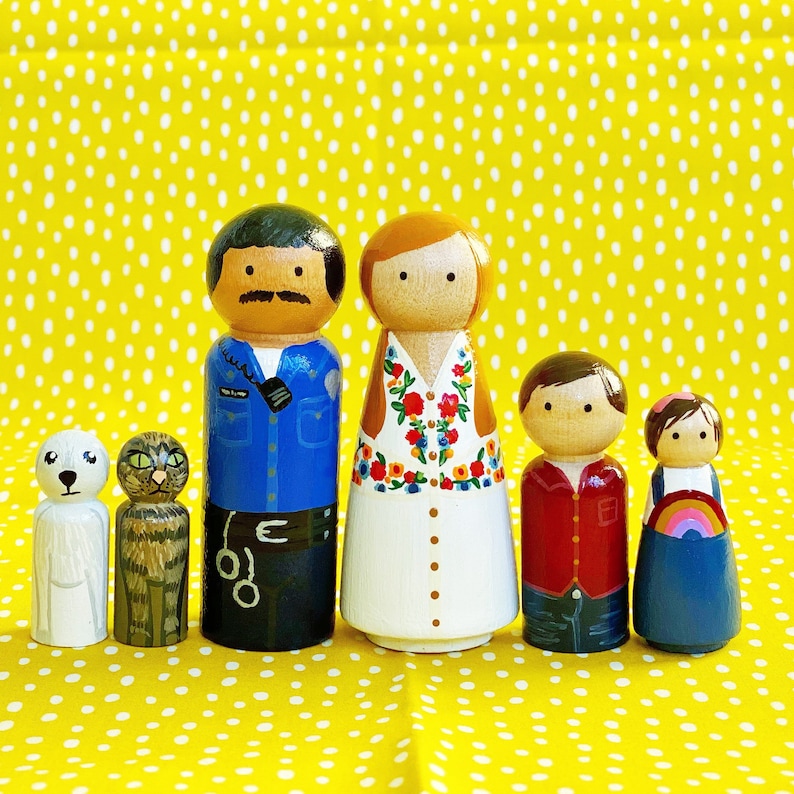 May include: A set of five wooden peg dolls, painted in various colors and designs. The dolls are dressed in different outfits, including a police officer uniform, a floral dress, a red shirt, and a blue dress. There are also two small white and brown animal dolls.
