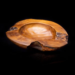 May include: A large, wooden bowl with a natural, rustic finish. The bowl is made from a single piece of wood and has a unique, organic shape. The bowl is perfect for serving fruit, snacks, or other small items.
