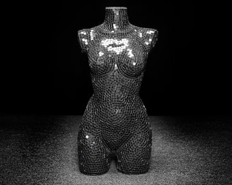 May include: A black and white mosaic torso mannequin. The mannequin is made of small, square tiles that create a textured surface.