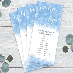 Può includere: Un programma per una cerimonia di matrimonio con uno sfondo acquerello blu. Il programma elenca l'ordine degli eventi della cerimonia di matrimonio, tra cui il preludio, la processione, il benvenuto, il congiungimento delle mani, i voti matrimoniali, lo scambio degli anelli, la lettura delle Scritture, la cerimonia del vino con musica, la dichiarazione di matrimonio e l'uscita degli sposi. Il programma è per il matrimonio di Michelle e Kyle sabato 15 agosto 2020.