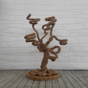 May include: A decorative tree sculpture made of brown rope, with a base made of wood. The tree is shaped like a bonsai tree, with branches that are twisted and curled.
