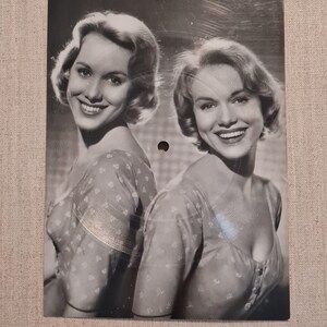 Può includere: Fotografia in bianco e nero di due donne sorridenti. Indossano camicette fantasia con bottoni. Entrambe hanno i capelli corti e mossi. L'immagine ha un'estetica vintage.