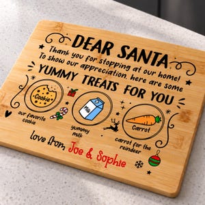 May include: A rectangular bamboo serving board engraved with the text DEAR SANTA, YUMMY TREATS FOR YOU, and love from Joe & Sophie. It features illustrations of a cookie, milk carton, and carrot, with labels for each item.