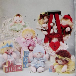 May include: A pattern envelope for "Luv 'n Stuff" featuring various handmade doll designs. The dolls have soft, plush bodies and are dressed in pastel colors. Some dolls are holding blocks that spell out "BOY" and "GIRL". The envelope is labeled "Butterick".