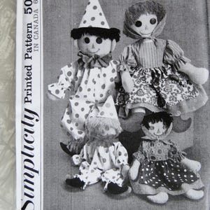 May include: Black and white image of a vintage Simplicity sewing pattern featuring four rag dolls. Two dolls are dressed as clowns in polka dot outfits and party hats. The other two dolls are wearing dresses. The pattern number is 257 and 6257.