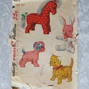 May include: A vintage Simplicity sewing pattern envelope 4915 featuring illustrations of four stuffed animals: a red polka-dot horse, a pink rabbit with striped details, a pink dog with plaid ears, and a yellow floral cat with a red bow.