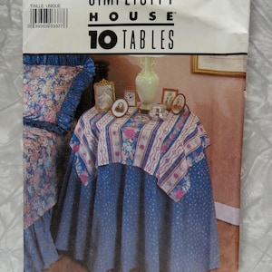 May include: Simplicity House pattern for 10 tables. The package features a blue and white floral table cover design. The package also includes a blue table skirt with white polka dots. The package has the number 8418 on the top left corner.