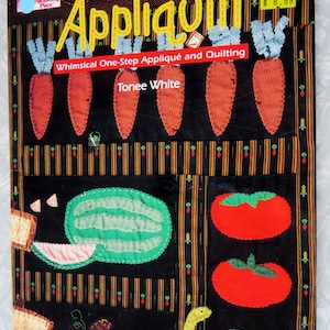 May include: A softcover instructional book titled Appliquilt: Whimsical One-Step Appliqué and Quilting by Tonee White. The cover features a black background with colorful fabric appliqués of carrots, a watermelon, tomatoes, and a green caterpillar.