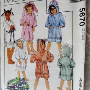 May include: McCall's pattern envelope featuring illustrations of children's hooded robes with animal-themed hoods. The robes are in various colors, including pink, blue, and orange. The pattern number is 5670.