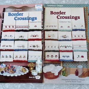 May include: Two books with colorful covers featuring embroidery patterns for kitchen towels. The books are titled "Border Crossings" and show a collection of designs for kitchen towels with various themes. The books are labeled "Collection One" and "Collection Two".