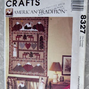 May include: A McCall's Crafts quilt pattern featuring an American Tradition theme. The pattern is for a quilt with a winter scene, including a snowman, trees, and houses. The pattern is called "American Tradition" and is number 8327. The pattern is for one envelope and includes instructions for foundation paper piecing.
