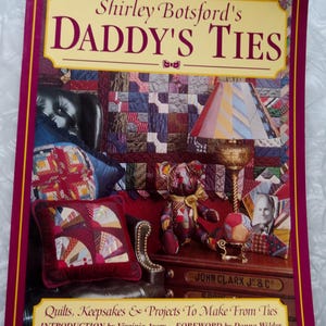 May include: A softcover book titled Shirley Botsford's Daddy's Ties: Quilts, Keepsakes & Projects To Make From Ties. The cover features a photograph of a room with a quilt, a lamp with a tie-patterned shade, a teddy bear, and a pillow made from ties.