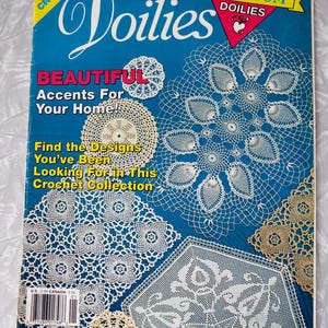 May include: A magazine cover titled "Favorite Doilies" with a blue background and various crochet doily designs. Text includes "Beautiful Accents For Your Home!" and "24 Heirloom Doilies".