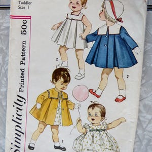 May include: Vintage Simplicity printed pattern 3843 for a toddler size 1. The pattern features illustrations of four different dresses and coats. The cover is off-white with the text "Simplicity Printed Pattern 50c".